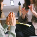 Two women engaged in a therapy session, communication and support in an office setting.