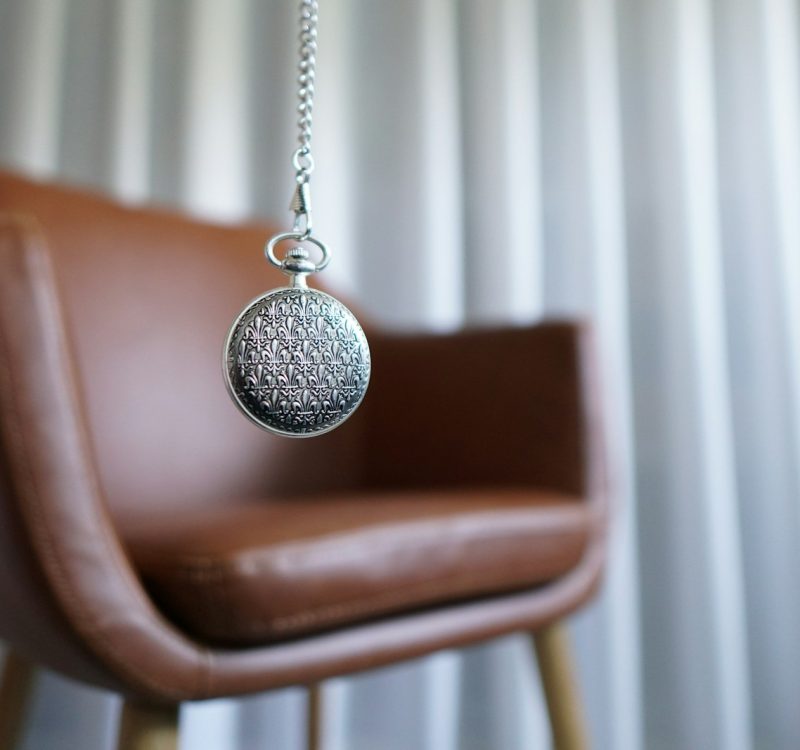 silver round pendant on brown wooden chair